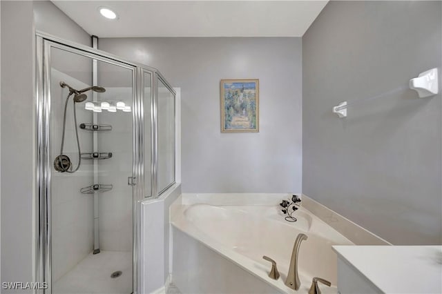 bathroom with a stall shower, a garden tub, and vanity