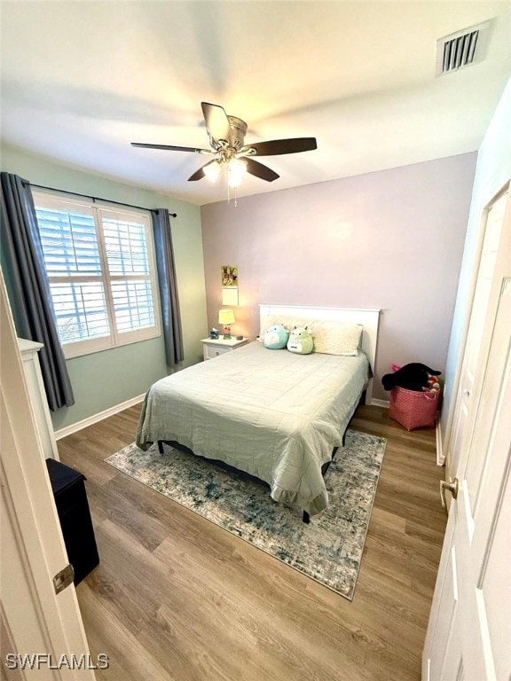 bedroom featuring a ceiling fan, baseboards, visible vents, and wood finished floors