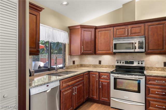 kitchen featuring sink, tasteful backsplash, light hardwood / wood-style floors, lofted ceiling, and appliances with stainless steel finishes