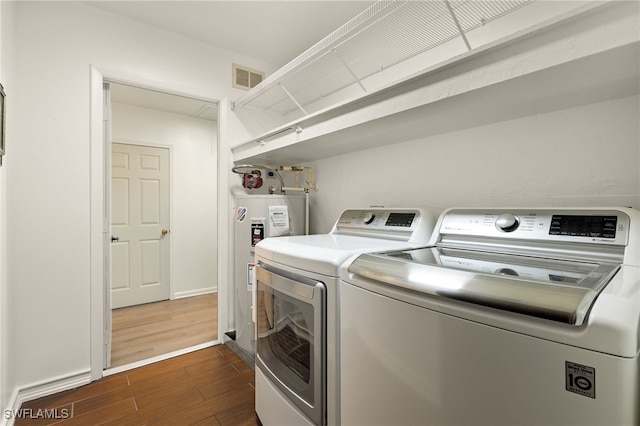 laundry room with electric water heater, dark hardwood / wood-style floors, and washing machine and clothes dryer