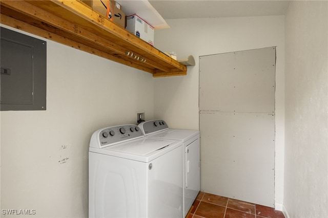 clothes washing area with electric panel, washer and clothes dryer, and dark tile patterned flooring