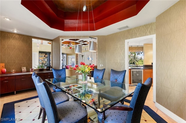 tiled dining space featuring a tray ceiling, wine cooler, and tile walls