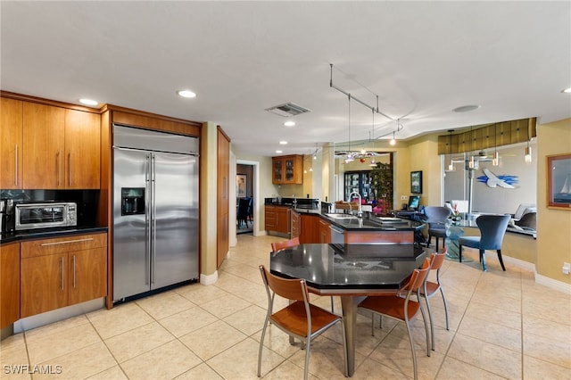 kitchen featuring sink, hanging light fixtures, track lighting, stainless steel built in fridge, and light tile patterned floors