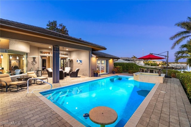 pool at dusk featuring outdoor lounge area and a patio