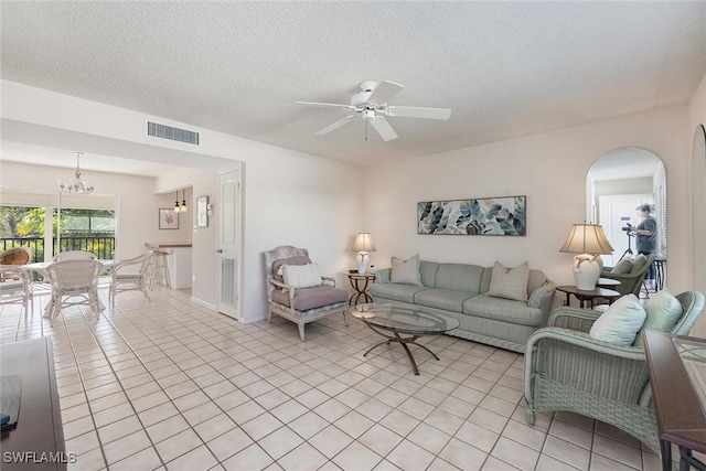 tiled living room featuring a textured ceiling and ceiling fan with notable chandelier