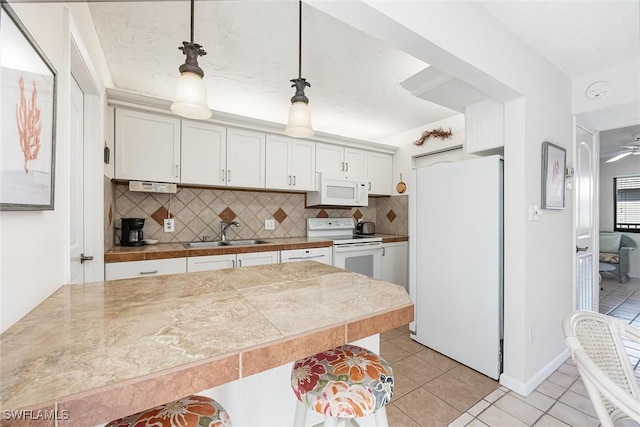 kitchen with decorative backsplash, white appliances, sink, decorative light fixtures, and white cabinetry