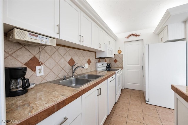 kitchen featuring decorative backsplash, white appliances, sink, light tile patterned floors, and white cabinetry