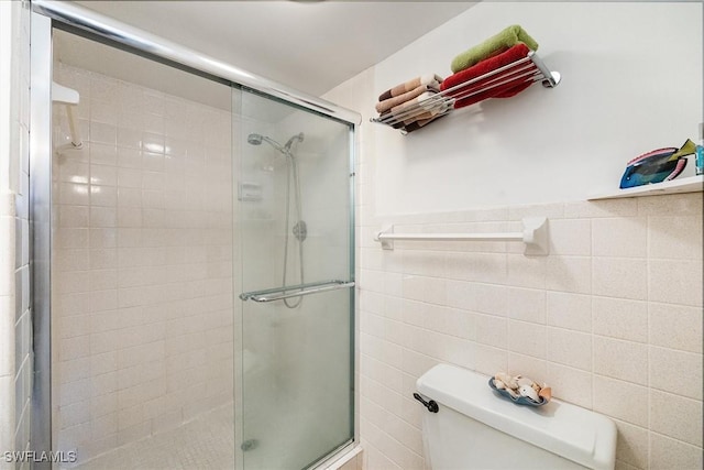 bathroom featuring an enclosed shower, tile walls, and toilet