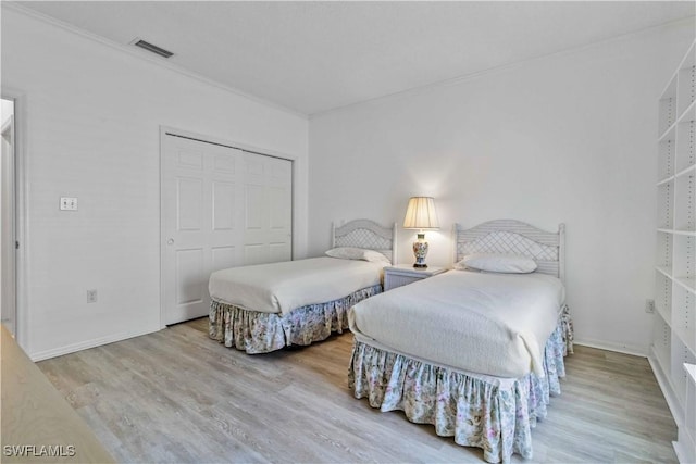 bedroom with crown molding, a closet, and light wood-type flooring