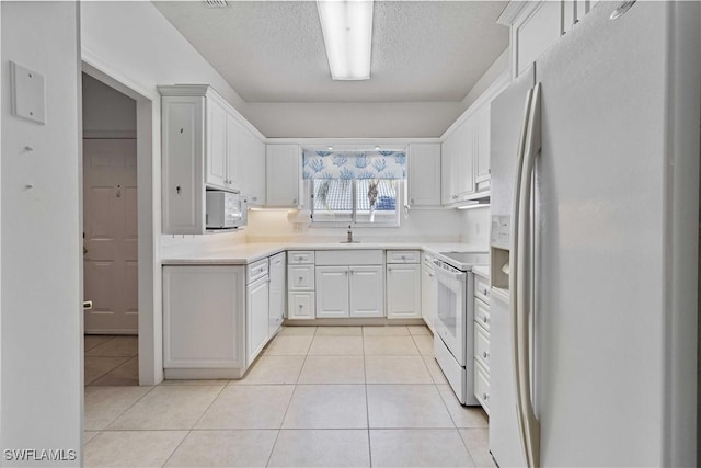 kitchen featuring light tile patterned floors, white appliances, a textured ceiling, and white cabinetry