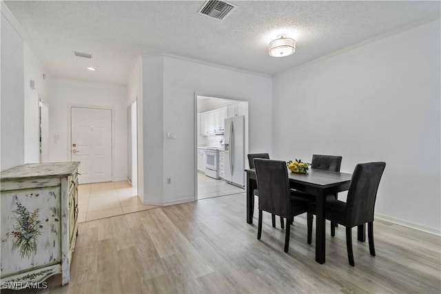 dining room featuring a textured ceiling, light hardwood / wood-style flooring, and crown molding