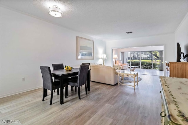 dining space with a textured ceiling and light hardwood / wood-style flooring