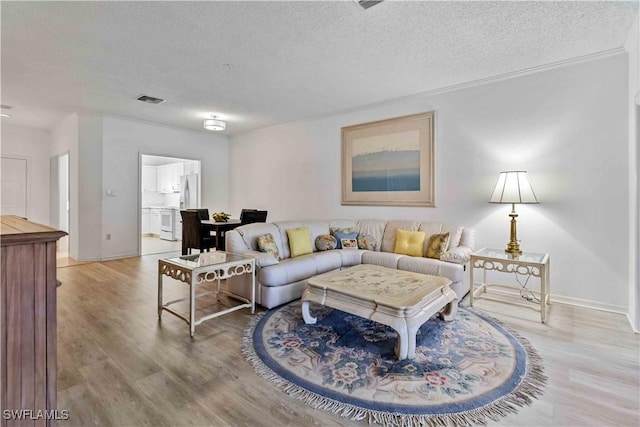 living room featuring ornamental molding, a textured ceiling, and light hardwood / wood-style flooring