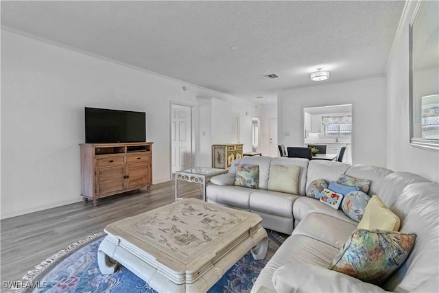 living room with crown molding, wood-type flooring, and a textured ceiling