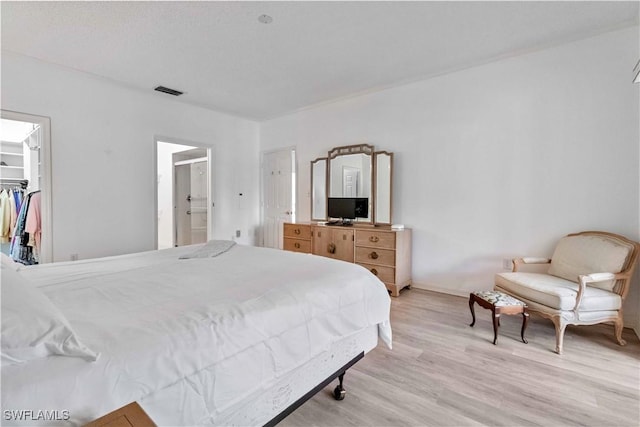 bedroom featuring ensuite bathroom, a spacious closet, a closet, and light hardwood / wood-style flooring