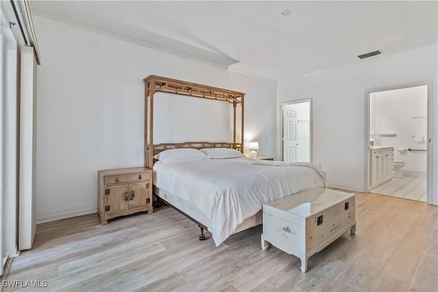 bedroom featuring ensuite bath, crown molding, a textured ceiling, and light wood-type flooring