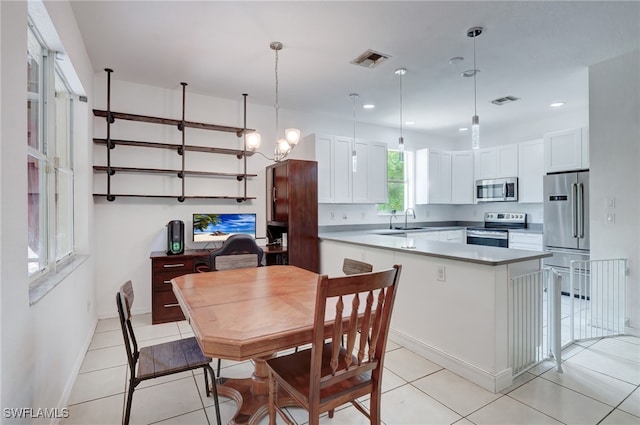 kitchen featuring decorative light fixtures, stainless steel appliances, white cabinetry, and sink