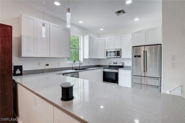 kitchen with sink, hanging light fixtures, light stone counters, white cabinets, and appliances with stainless steel finishes