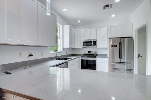 kitchen featuring light stone countertops, appliances with stainless steel finishes, white cabinetry, and sink