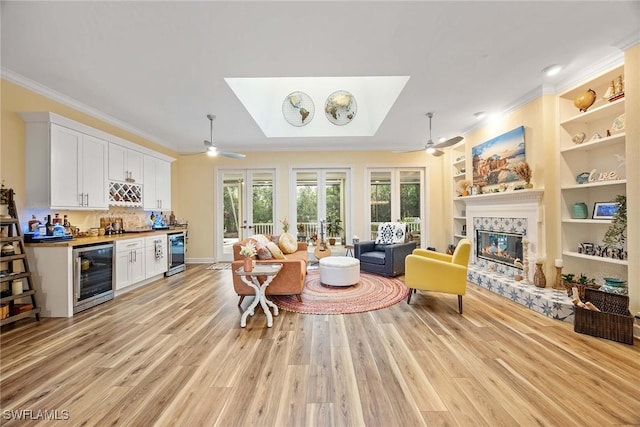 living room with bar area, crown molding, beverage cooler, and a fireplace