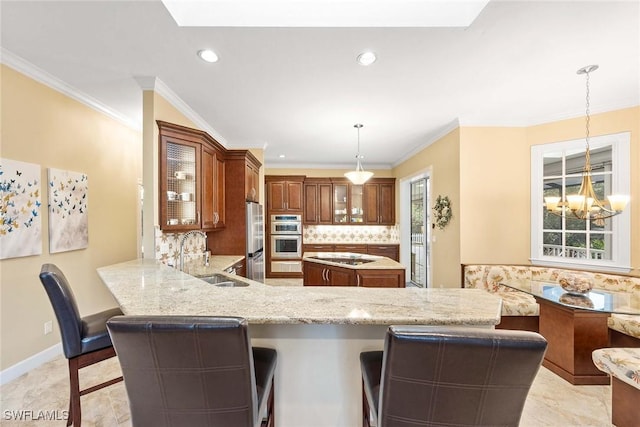 kitchen with kitchen peninsula, decorative light fixtures, sink, backsplash, and a kitchen breakfast bar