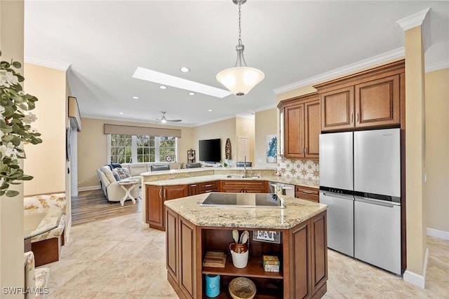 kitchen featuring appliances with stainless steel finishes, a skylight, a center island, sink, and kitchen peninsula