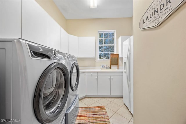 laundry room with light tile patterned floors, sink, washer and clothes dryer, and cabinets