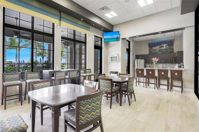 dining area featuring a drop ceiling and light wood-type flooring