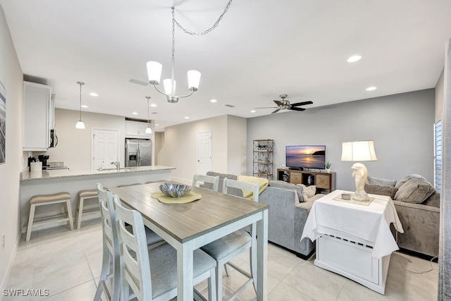 dining space with ceiling fan with notable chandelier, light tile patterned flooring, and sink