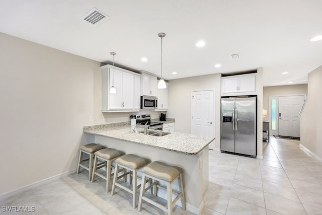 kitchen featuring kitchen peninsula, a kitchen breakfast bar, stainless steel appliances, white cabinets, and hanging light fixtures