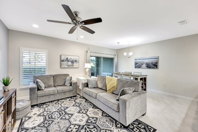 living room featuring ceiling fan with notable chandelier and light tile patterned floors