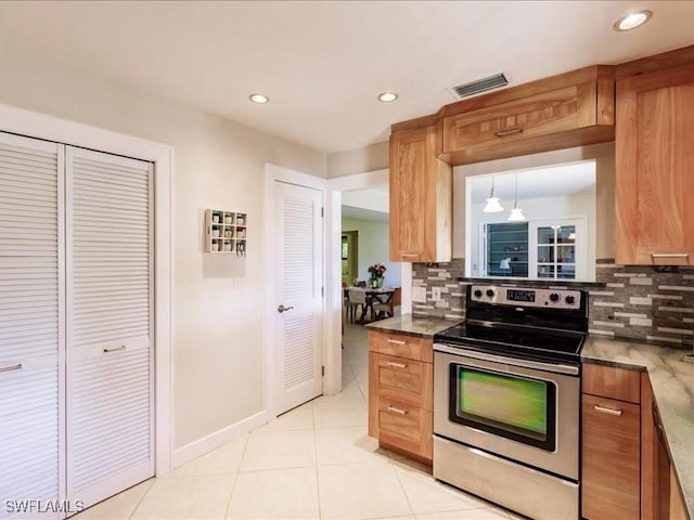 kitchen featuring stainless steel electric stove, backsplash, light tile patterned flooring, and hanging light fixtures