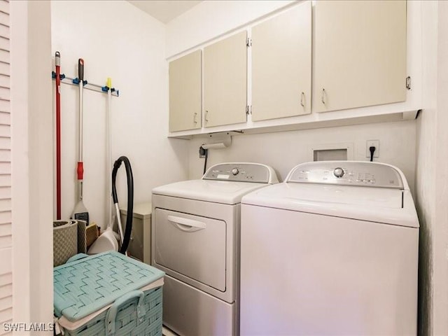 washroom with washing machine and clothes dryer and cabinets