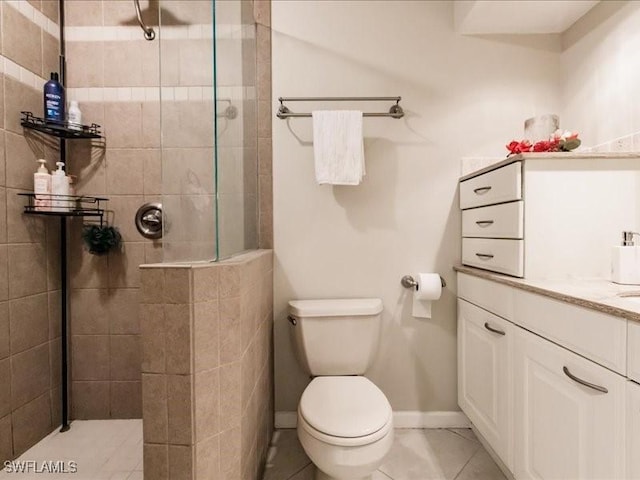 bathroom with tiled shower, vanity, tile patterned flooring, and toilet