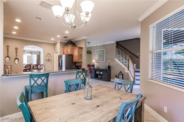 dining room with a healthy amount of sunlight, light tile patterned floors, crown molding, and a chandelier