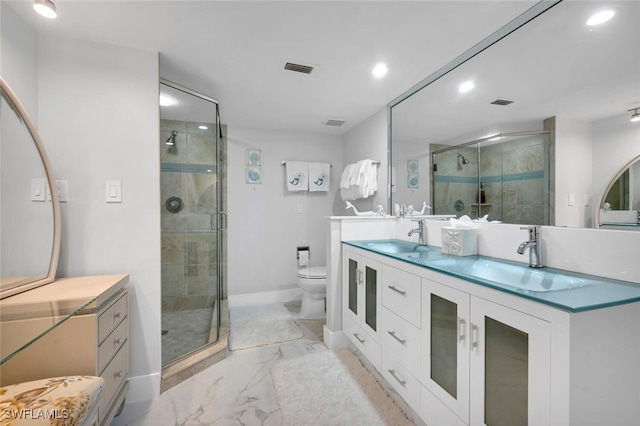 bathroom featuring vanity, a shower with shower door, and toilet