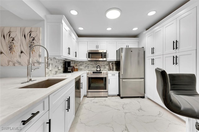 kitchen with light stone countertops, sink, white cabinets, and stainless steel appliances