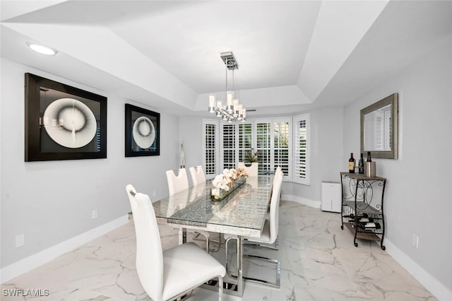 dining space featuring a notable chandelier and a tray ceiling