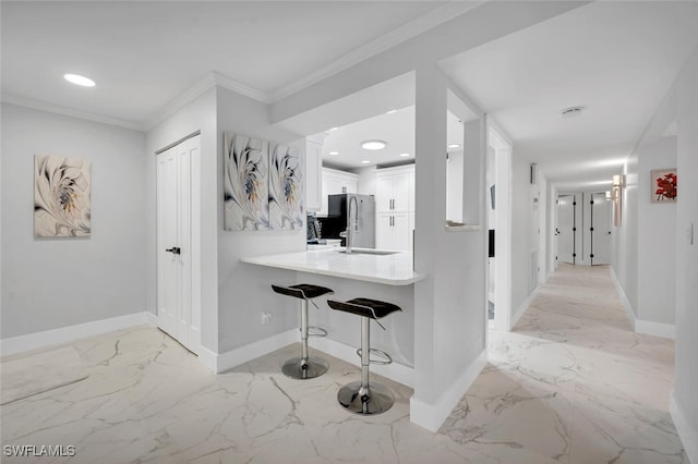 kitchen featuring kitchen peninsula, a breakfast bar, crown molding, sink, and white cabinetry