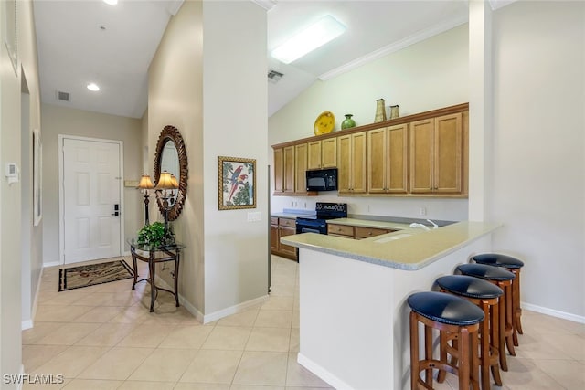 kitchen with sink, kitchen peninsula, a breakfast bar area, light tile patterned floors, and black appliances