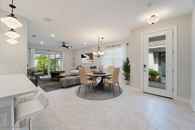 tiled dining space with ceiling fan with notable chandelier and plenty of natural light