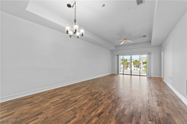 empty room featuring dark hardwood / wood-style floors, ceiling fan with notable chandelier, and a tray ceiling