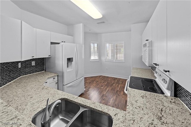 kitchen featuring decorative backsplash, white appliances, sink, white cabinets, and dark hardwood / wood-style floors