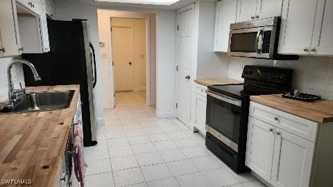 kitchen with butcher block countertops, white cabinetry, sink, and black range with electric cooktop