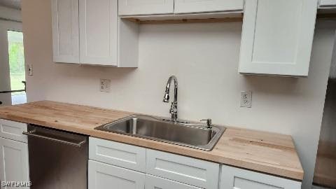 kitchen featuring stainless steel dishwasher, white cabinets, and butcher block counters