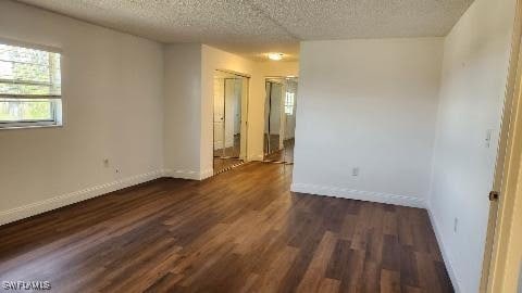 spare room featuring a textured ceiling and dark hardwood / wood-style floors