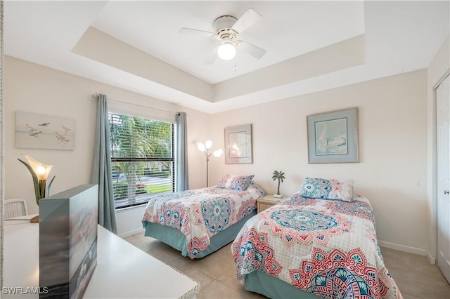 bedroom featuring ceiling fan, light tile patterned floors, and a tray ceiling