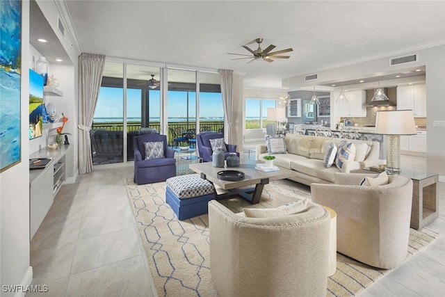 tiled living room with ceiling fan and ornamental molding