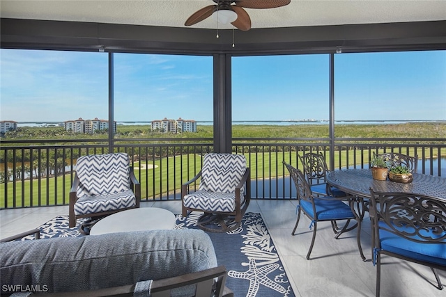 sunroom / solarium with a water view and ceiling fan