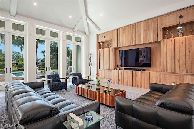 carpeted living room with beam ceiling, wooden walls, and french doors